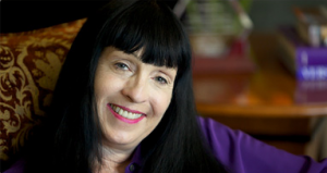 A smiling woman with long black hair and bangs.