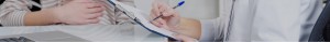 Person holding a pen poised to write on a notebook.