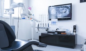 Modern dental clinic setup with equipment and digital X-ray on screen.