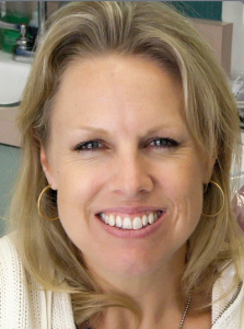Smiling woman with blonde hair and hoop earrings.