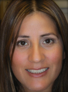 Close-up portrait of a smiling woman with brown hair and brown eyes.