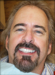 Close-up of a smiling man with a beard and mustache.