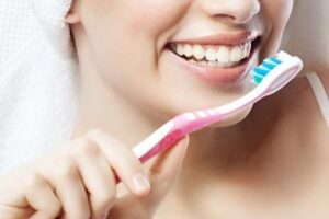 Smiling person holding a toothbrush.