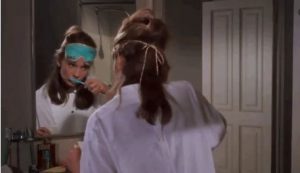 A woman brushing her teeth while looking in the mirror.