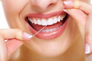 Close-up of a person flossing their teeth with a bright smile.