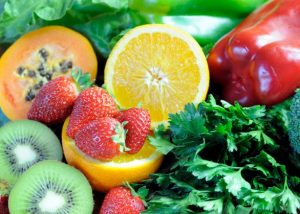 Fresh fruits and vegetables including strawberries, orange, and leafy greens.