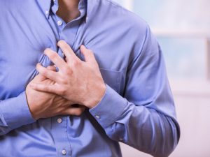 Man clutching his chest in pain, possibly experiencing heart trouble.