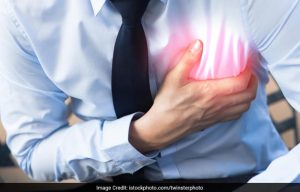 A man clutching his chest in apparent heart pain, wearing a shirt and tie.