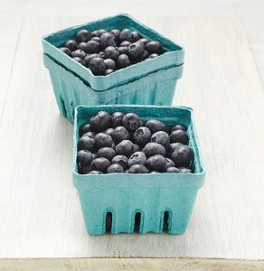 Two blue containers filled with fresh blueberries on a white surface.